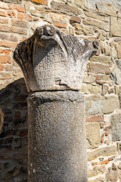 Ancient stone column capital showing historical inscription in Cortona, Italy