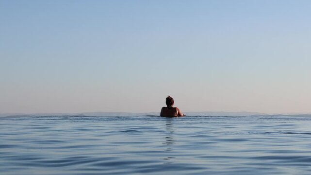 Woman watching the sunset from an infinity pool