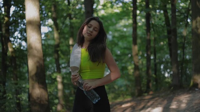 This active female lifestyle clip is perfect for health, wellness, and motivational commercial projects.This high-quality video shows a young sporty girl in a green sweatshirt and black shorts drinki