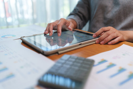 Businessperson reviewing financial dashboards and business reports on a touchscreen tablet, analyzing data to support planning and informed decisions.