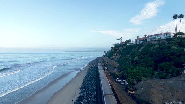 A drone glides above the Orange County Surf Liner as it travels from San Clemente to San Juan Capistrano. This cinematic view of the train traveling alongside the Pacific Ocean is Breathtaking.