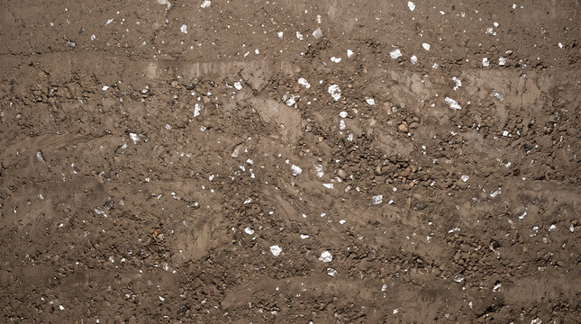 Rammed earth wall texture background. Natural soil construction surface with stone aggregate.