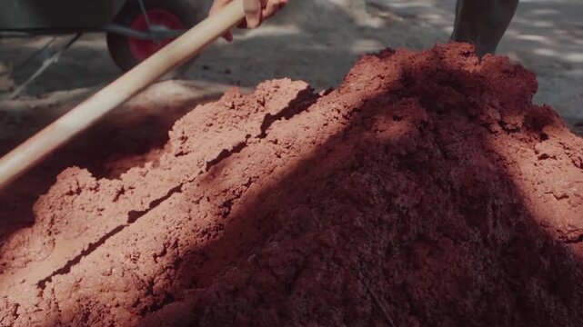 Indigenous person mixing clay and sand for bioconstruction in Brazil. Wattle and daub building method for eco friendly housing