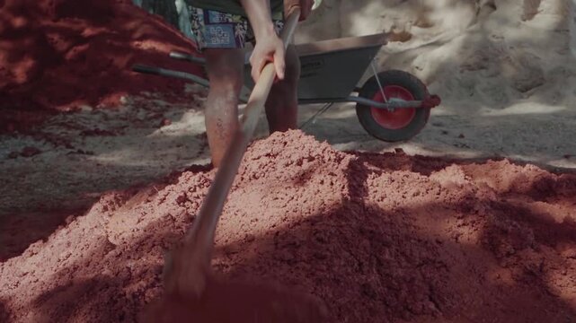 Low angle view of an indigenous man kneading clay and sand barefoot. Traditional wattle and daub building method for sustainable housing