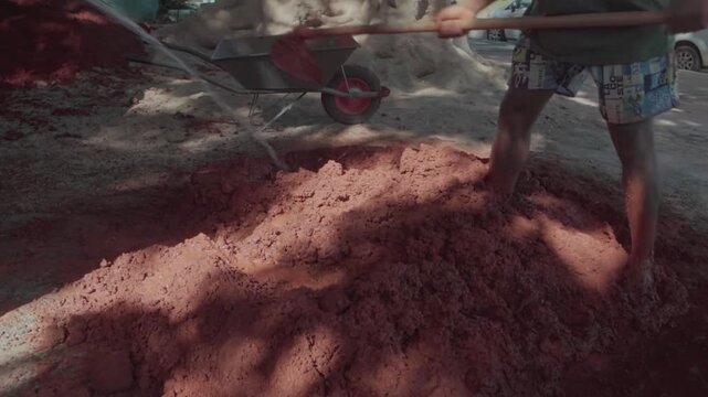 Slow motion of a worker mixing clay and sand with a shovel. Preparation of natural material for a sustainable and ecological building