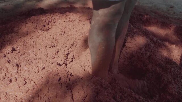 Worker mixing clay, sand, and straw with a shovel for a natural building project. Eco friendly wattle and daub construction in Brazil