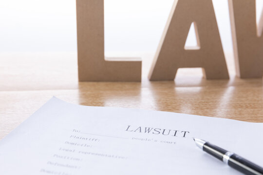 Lawsuit document with pen and law letters on desk