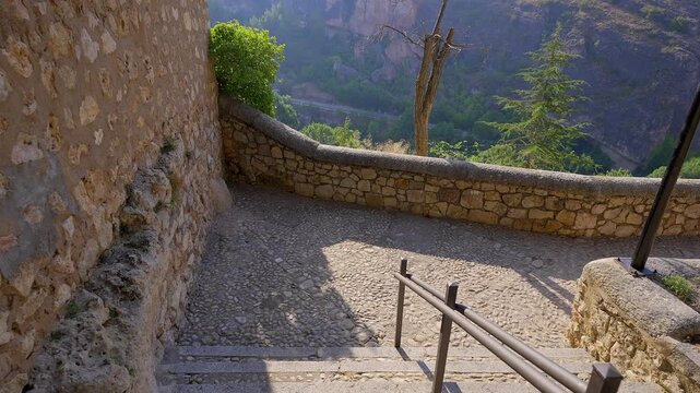 Sunlit stone wall overlooking cliffs and trees in the Huecar valley beside San Andres Cuenca