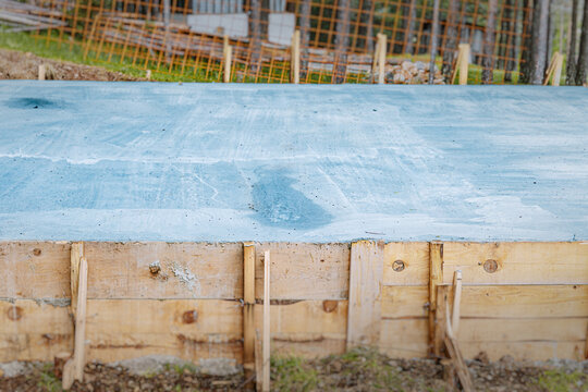 Freshly poured concrete slab on wooden formwork at a residential construction site. Building concept.