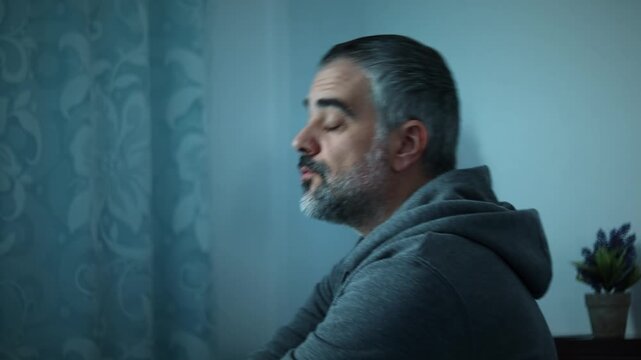 Stressed man thinking in dim light, medium shot, sits down