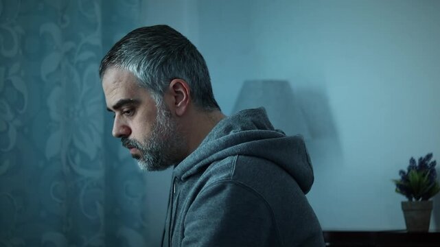 Worried man sitting alone in dark room, close up, sits down