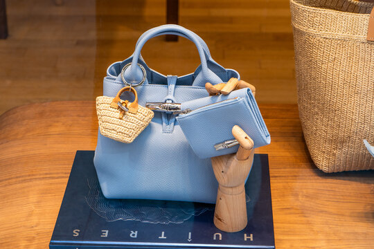 Longchamp Light Blue Leather Handbag with a Mini Woven Basket Charm, Wallet and Wooden Hand Display in store shop on street. Verona, Italy - June 25, 2026