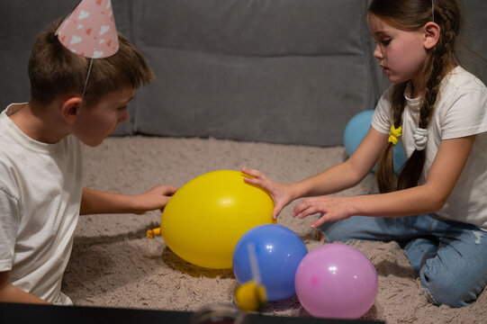 Children joyfully playing with colorful balloons while celebrating a birthday party in a cozy indoor setting during the evening