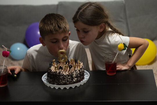 Celebrating a special birthday with excited children, a delicious chocolate cake adorned with candles, and joyful decorations in a cozy room filled with balloons