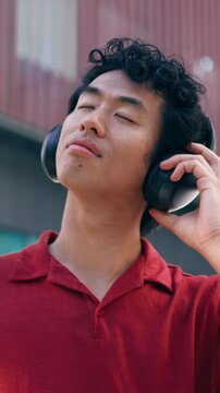 Video of cheerful man listening music with headphones on the street