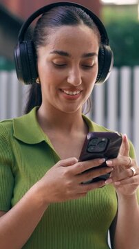 Video of beautiful woman using smartphone while listening music with headphones on the street