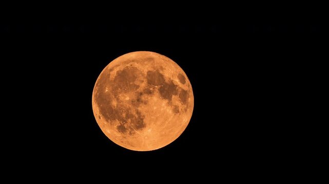 Massive orange full moon rising on black background time lapse