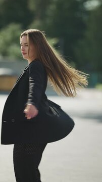 Beautiful young woman spinning around with flying hair on a city street, slow motion