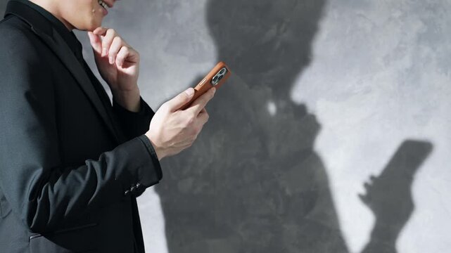 Silhouette of a man using a smartphone. Social media, apps, email, videos, serious, anxiety, worry, fraud.
