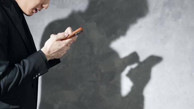Silhouette of a man using a smartphone. Worrying, trouble, problems, feeling flustered, in a bind, questions, serious, crime.