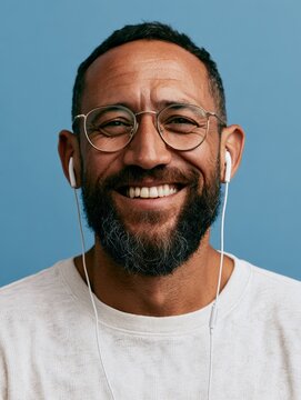 Smiling Man with Beard, Headphones, and Earbuds in a Studio Portrait