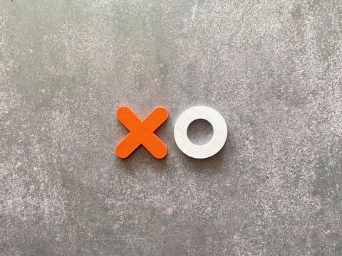 Minimalist X and O game pieces on a textured background representing strategy, competition and decision making.