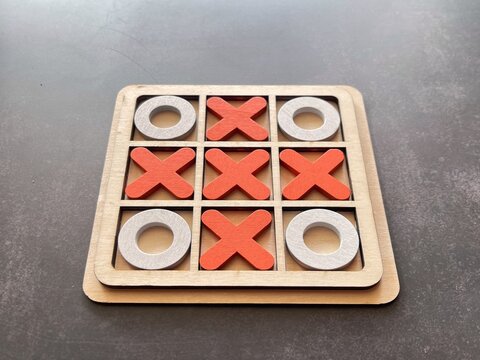 Wooden tic tac toe board showing a winning move, symbolizing strategic thinking, planning and problem solving.