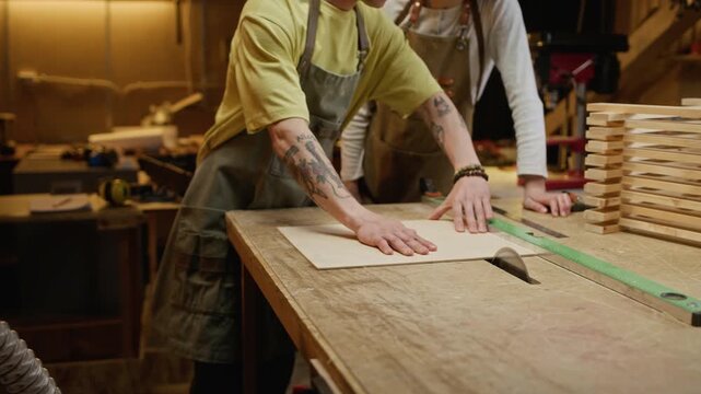 Caucasian young adult male and female carpenters wearing aprons performing woodworking project in workshop. Clip is perfect for promoting vocational training or small business entrepreneurship
