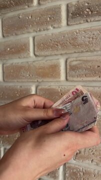 Woman's hands counting turkish lira banknotes against a brick wall, illustrating financial transactions, budgeting, and the economy of turkey with close up detail on currency