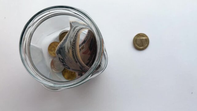 Person saving money by putting coins and dollar bills into a glass jar for investment and financial security on a white background, representing budgeting and savings