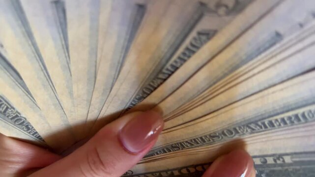 Woman holding fanned american fifty dollar bills, showing wealth, financial success, and prosperity, a close up view of currency and manicured fingers counting cash money