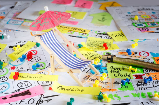 beach chair and sun umbrella on cluttered office desk. Business concept  annual travel, vacation and holidays concept
