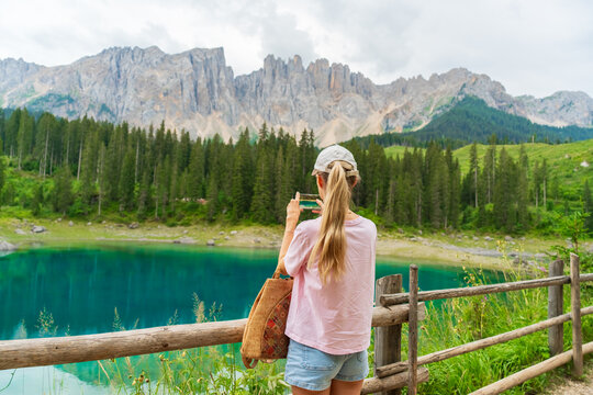 Tourist photographing turquoise mountain lake in the Italian Dolomites. Travel, social media, outdoor adventure, digital nomad and sustainable tourism concept in the Italian Dolomites
