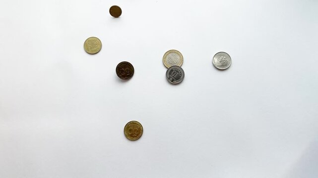 Various metal coins falling from above onto an isolated white background, representing concepts like economy, wealth, investment, savings, profit, and financial crisis