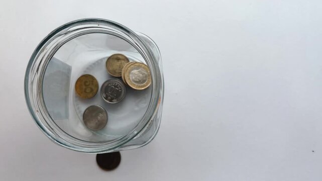 Saving ukrainian hryvnia coins in a glass jar for financial investment, accumulating small change for future economy growth and building wealth with a piggy bank