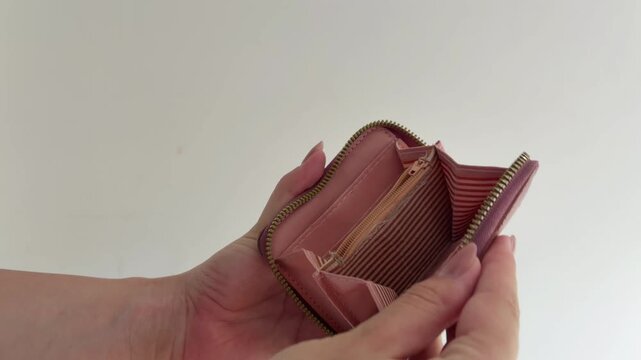 Woman's hands opening an empty pink wallet with heart details isolated on a white background, symbolizing poverty, debt, bankruptcy, and financial crisis