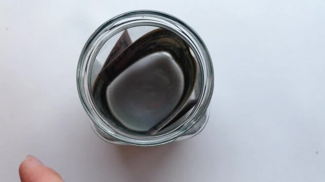 Saving american dollars in glass jar for future investment, household budgeting, and financial planning for retirement isolated on white background, top view concept video