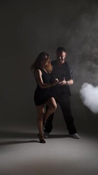 Elegant couple dancing Latin dance or tango in dark studio, passion and motion concept.