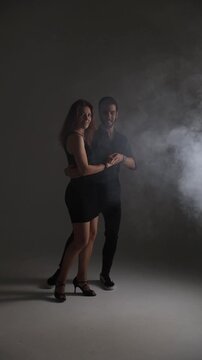 Elegant couple dancing Latin dance or tango in dark studio, passion and motion concept.