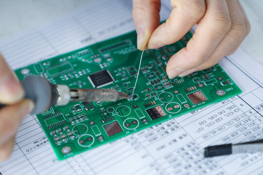 Hands soldering electronic circuit board during precision assembly