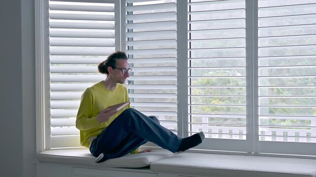 Man Walking Near Window Holding Book in 4K