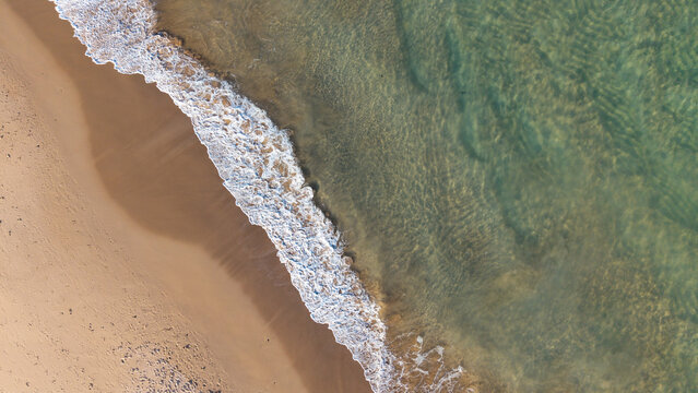 Aerial view of the sandy shoreline and turquoise waves crashing onto the beach at Dee Why, New South Wales, Australia.
