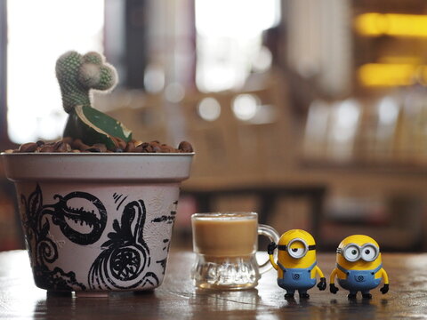Indonesia - March 10, 2019 : Mini toy of action figure at table with blurred background. Toy photography concept. Minion character at cafe with green grass conceptual design.