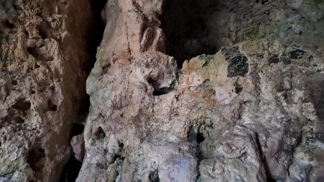 Xemxija, Malta 29.07.2026 - Heritage trail, Roman Baths, shelf like cut in the stone Dark cave walls show rough, textured surfaces. Greenish moss grows on damp, uneven stone. Light filters through nar