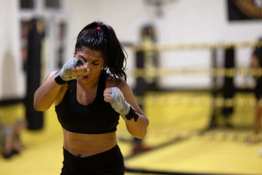 Female Boxer Training in Gym Throwing Punches During Intense Fitness Session in Boxing Ring