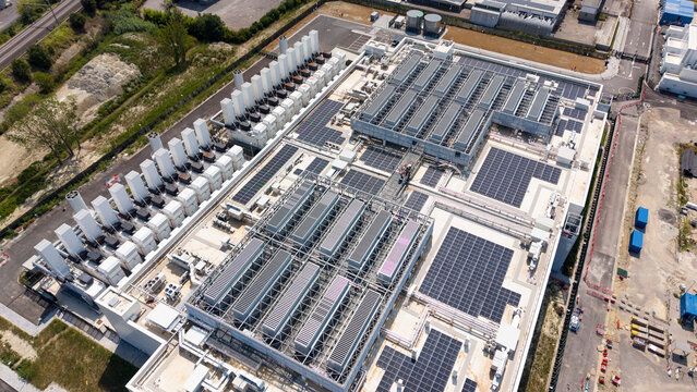 Aerial view of a modern AI data center facility featuring extensive rooftop solar panels and industrial cooling units in Melegnano, Lombardy, Italy.