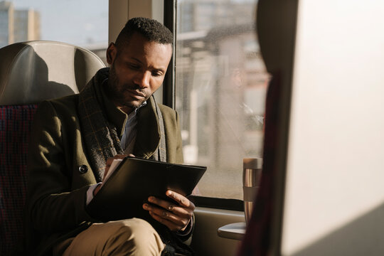 Stylish businessman taking notes while traveling by train