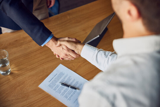 Recruiter shaking hands with candidate at desk
