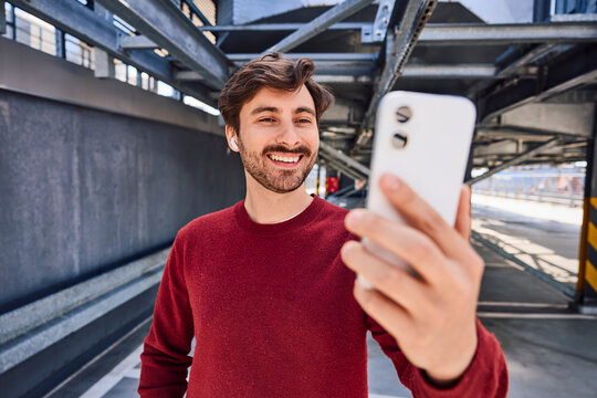 Cheerful selfie with smartphone in parking garage