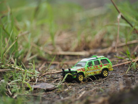 Indonesia - November 15, 2020 : Adventure, holiday and traveling conceptual design with mini toy. Blurred outdoor view. Unfocus stuff. Blurred green grass as a background. Conceptual photography.